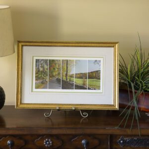A framed picture on a table next to a lamp.