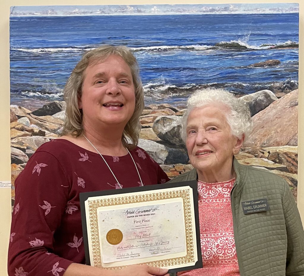 201 A woman is holding a certificate in front of a painting.