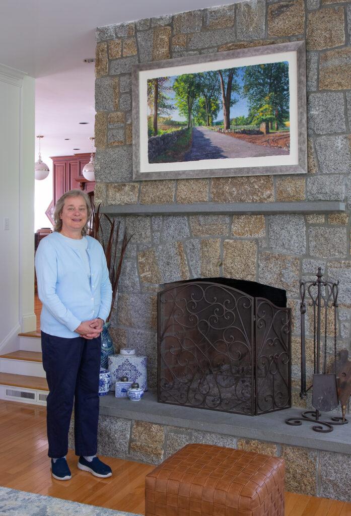 A woman standing in front of a stone fireplace.
