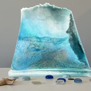 A glass sculpture of an iceberg surrounded by seashells.