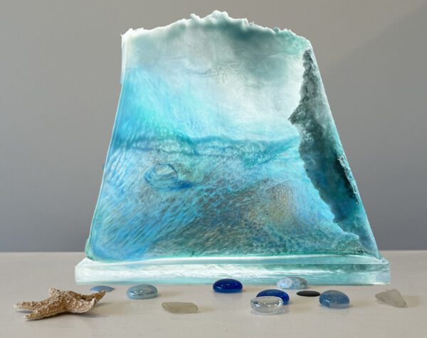 A glass sculpture of an iceberg surrounded by seashells.