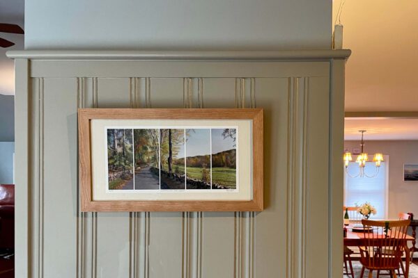 An Autumn River, Road, small print in a beveled frame 18.25 x 12.25 x 1 inches hangs on the wall of a dining room.