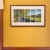 A framed photo of Autumn, River Road, small print in a combed wooden frame 12.5 x 18.5 x 2-inches in a room with yellow walls.