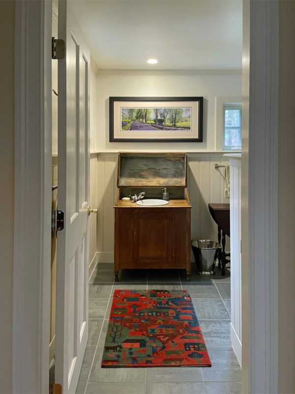 A bathroom with a SOLD. June, River Road, in a red wooden frame, 35.5 x 17.5 x 1 inches and a rug on the floor.