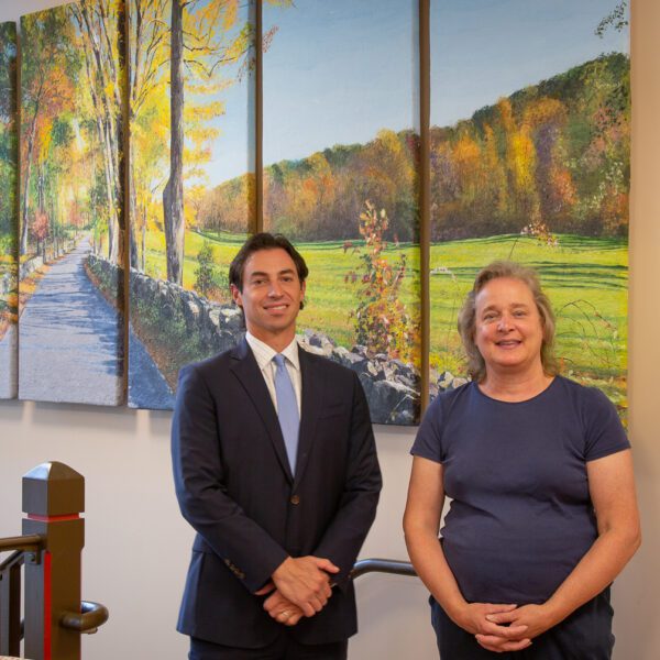 Two people standing in front of a painting.