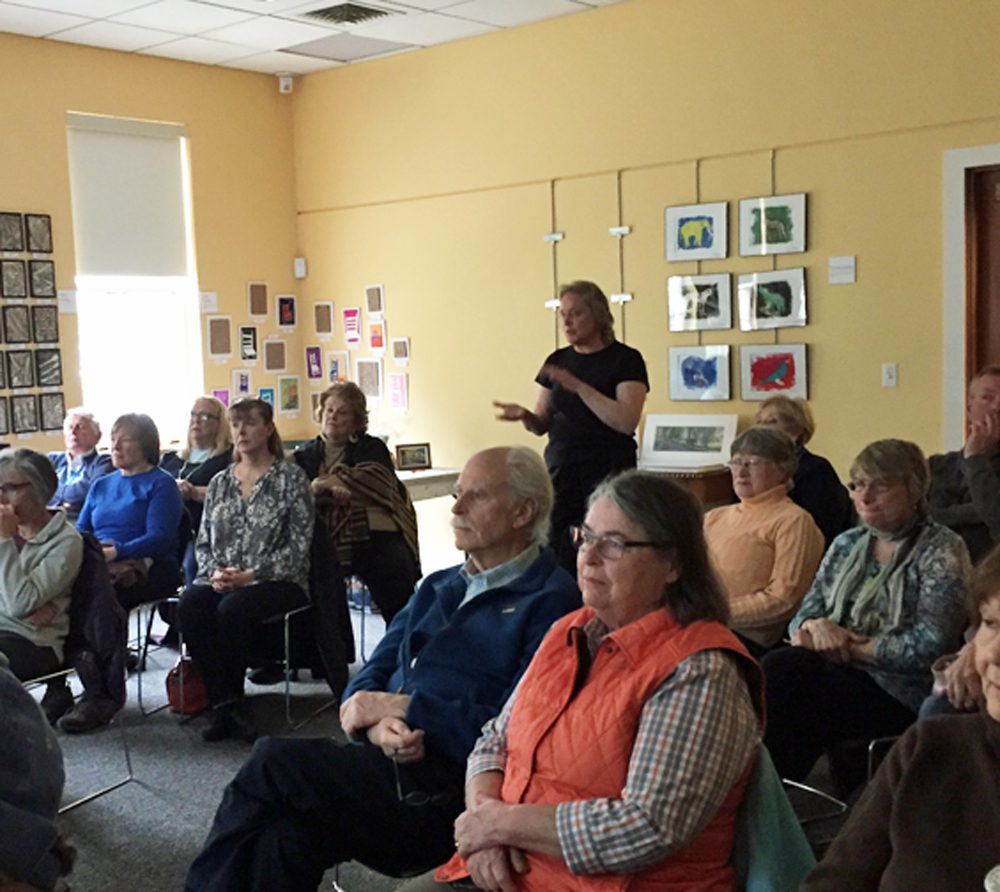 A group of people sitting in a room listening to a speaker.