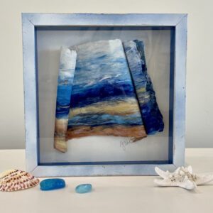 A framed piece of art with seashells and seaweed.