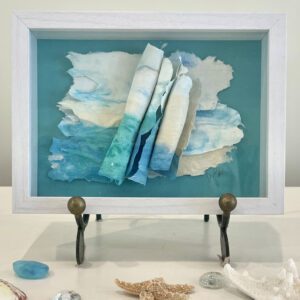 A framed piece of paper with seashells and a starfish.