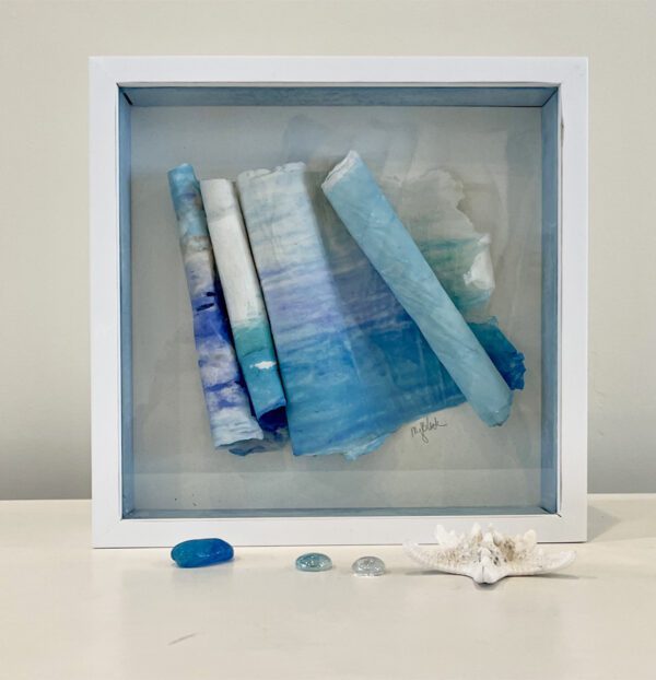 A white frame with blue and white paper and sea shells.