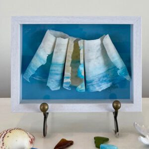 A framed piece of sea glass with a shell on it.