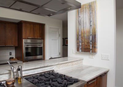 A kitchen with stainless steel appliances and a large painting.
