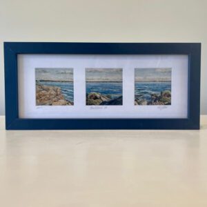 Three framed pictures of the ocean in a blue frame.