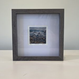 A black frame with a photo of a rocky beach.