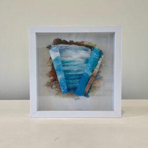 A white frame with a blue and white painting on it.