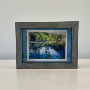 A picture of a river in a frame on a table.