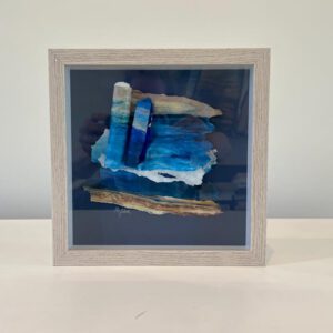 A framed piece of sea glass in a white frame.
