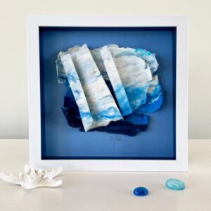 A blue and white framed piece of sea glass.