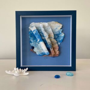 A framed piece of seashells and a blue frame.