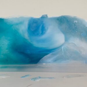 A translucent blue and white soap bar with swirls, displayed on a white surface with droplets visible.
