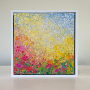 Impressionist-style painting featuring vibrant, textured brushstrokes of yellows, pinks, and greens in a white frame on a beige surface.