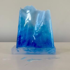 A translucent blue resin sculpture resembling icy peaks, displayed against a neutral background.