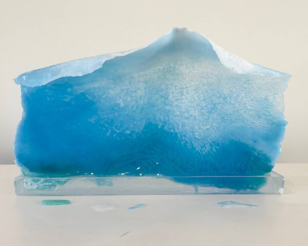 A translucent blue resin sculpture resembling an iceberg, displayed against a white background.