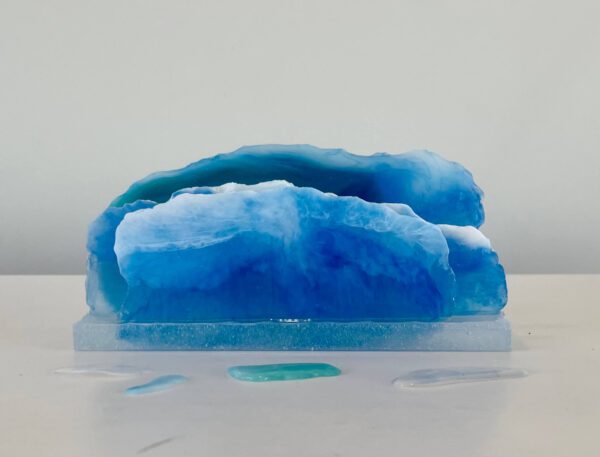 A translucent blue resin sculpture resembling layers of an iceberg, displayed on a neutral background with soft lighting.