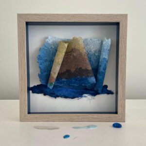 Framed abstract paper art with blue hues.